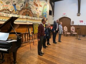 6 people bow in front of tapestry
