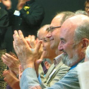 a row of heads in an audience applauding